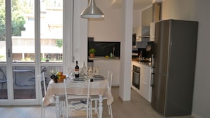 Una cocina moderna con un refrigerador de acero inoxidable, una mesa de comedor lista con platos, vasos y una botella de vino.