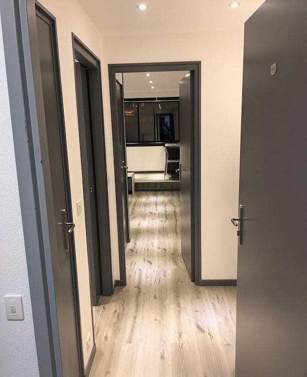 Ein Flur mit Holzboden, der zu einem Küchenbereich mit Schränken und Arbeitsplatte führt.