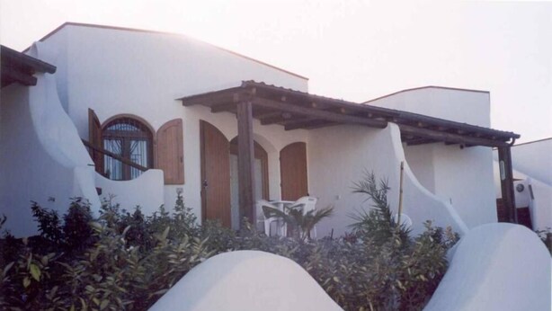 Una casa moderna con una fachada ondulada original, un porche cubierto y un pequeño jardín.