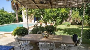 A covered outdoor dining area with a table and chairs, a decorative pot, and a view of a swimming pool and garden. - SALENTO VILLA WITH POOL, GARDEN, TERRACES, NEAR THE SEA OF CASTRO (DISO)