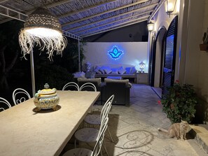En udendørs patio med spisebord, stole, en dekorativ vase og en kat.