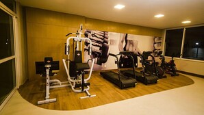 Un gimnasio con equipo cardiovascular, máquinas de pesas y un cartel grande en la pared.
