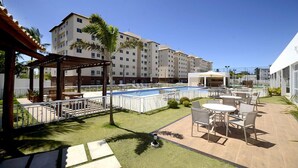 Un patio de hotel con piscina, mobiliario exterior y zona cubierta.