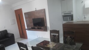 Una cocina moderna con microondas integrado, un mueble de madera y una mesa de comedor de vidrio con sillas.