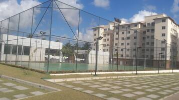 Una cancha deportiva cercada con un edificio al fondo.