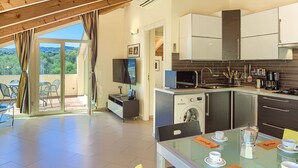 Een moderne keuken met een ingebouwde wasmachine, een eetgedeelte met een glazen tafel en uitzicht op de omgeving.