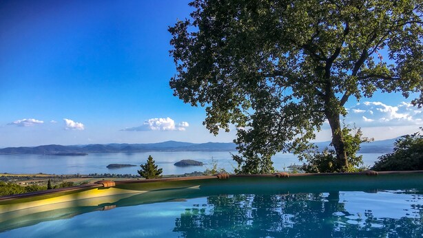 Una piscina infinita con vistas despejadas a un lago y montañas distantes.