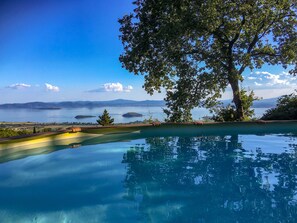 Una piscina infinita con vistas despejadas a un lago y montañas distantes.