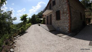 Una casa de piedra con camino de grava y escalones que conducen a una puerta de madera.