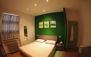 A bedroom with a bed, a nightstand, a mirror, a radiator, and a green wall with three animal-themed pictures.