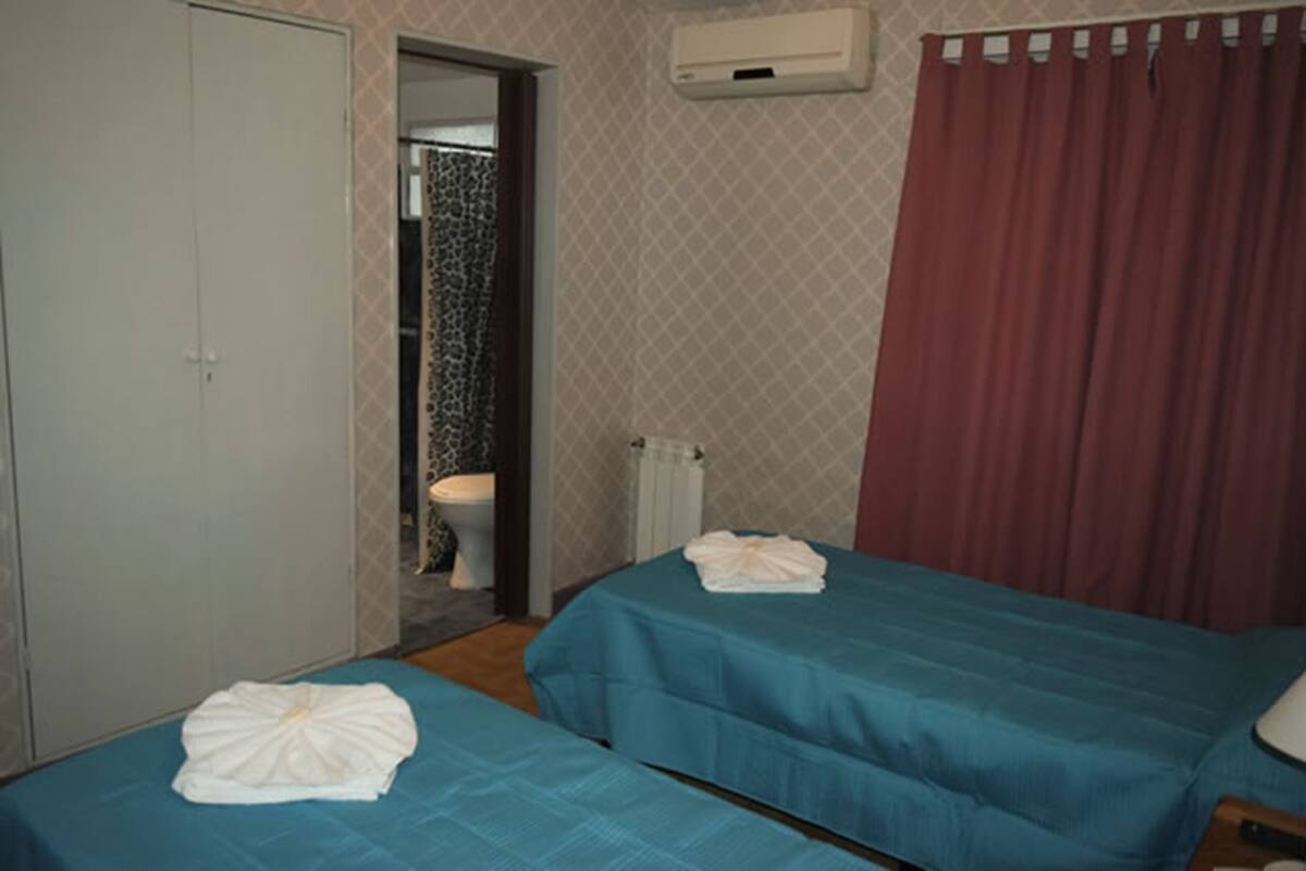Ein Hotelzimmer mit zwei Betten, einem Badezimmer und einem roten Vorhang.