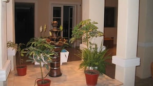 A hallway with multiple potted plants, a white pillar, and a door in the background. - Hotel Bella Vista (Villa Carlos Paz)