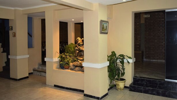 A lobby with a central planter, a staircase, and a brick wall. - Hotel Bella Vista (Villa Carlos Paz)