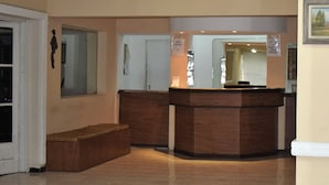 A reception area with a wooden reception desk, a bench, and a potted plant. - Hotel Bella Vista (Villa Carlos Paz)