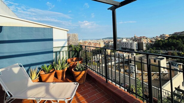 Un balcon avec une chaise blanche, des plantes en pot et une vue sur la ville.