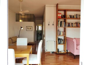 Un salon avec une table en bois, un canapé blanc et une bibliothèque remplie de livres.