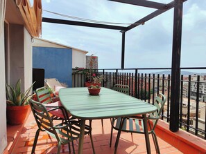 Un balcon avec une table et des chaises, des plantes en pot et une vue sur la ville.