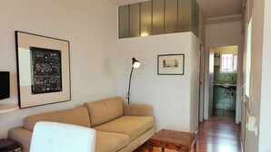Un salon avec un canapé, une petite table en bois, un lampadaire et un tableau encadré au mur.