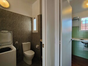 Une salle de bain avec des toilettes, une petite fenêtre et un lavabo.