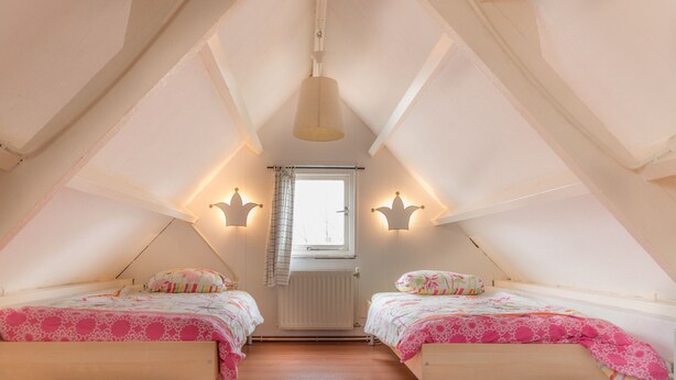 Una habitación con dos camas, una ventana con cortinas y un radiador.