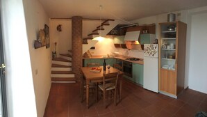 Une cuisine de taille réduite comprenant une table à manger, des chaises, une cuisinière et un réfrigérateur.