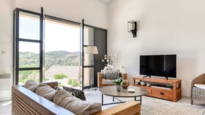 A modern living room with a sofa, a coffee table, a TV, and a view of the outdoors. - Between land and sea in the Cathar region (Durban-Corbières)