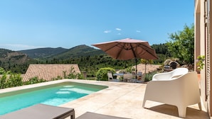 A pool area with lounge chairs and an umbrella, surrounded by a hilly landscape. - Between land and sea in the Cathar region (Durban-Corbières)