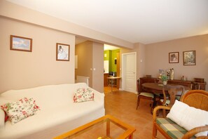 A living room with a sofa, a dining table with chairs, and a kitchen area in the background. - house / villa - Hendaya with swimming pool (Hendaye)