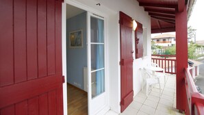 A balcony with red shutters, a white chair, and a view of a residential area. - house / villa - Hendaya with swimming pool (Hendaye)