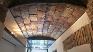 Un techo abovedado de ladrillo con tragaluces, una viga de madera y una escalera parcialmente visible.
