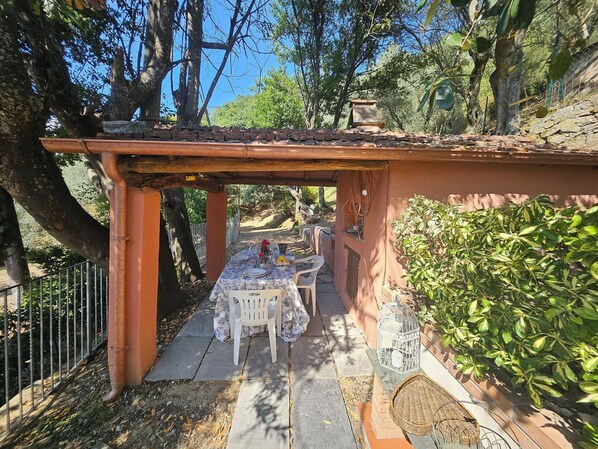 An outdoor dining area with a pergola, a table set for two, and a birdcage.