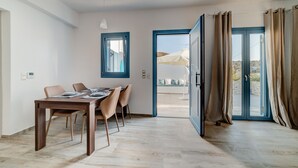 Un comedor moderno con una mesa y sillas de madera, un ventanal con marco azul y vistas al exterior a través de un vidrio.