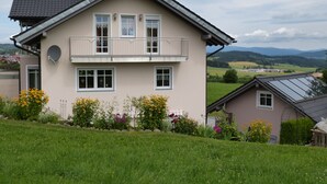 A two-story house with a balcony, surrounded by a well-maintained garden with various flowers. - Family-friendly 4 * Holiday, Pets Allowed, N. Ground corn, Hiking (Kirchberg i. Wald)