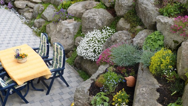 A garden with a stone wall, various plants, and a table with chairs. - Family-friendly 4 * Holiday, Pets Allowed, N. Ground corn, Hiking (Kirchberg i. Wald)