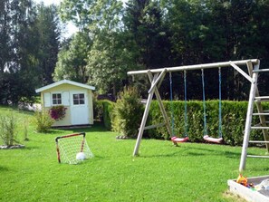 Enjoy a peaceful retreat in our outdoor play area, featuring a swing set, shed, and soccer goal amidst lush greenery.