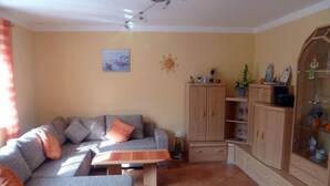 A living room with a grey sofa, a wooden cabinet, and a tiled floor. - Family-friendly 4 * Holiday, Pets Allowed, N. Ground corn, Hiking (Kirchberg i. Wald)
