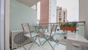 A balcony with a table and chairs, a potted plant, and an air conditioning unit. - Rent Corro X32 (Córdoba)