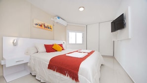 A modern hotel room with a large bed, white walls, a flat-screen TV mounted on the wall, and a window providing natural light. - Rent Corro X32 (Córdoba)