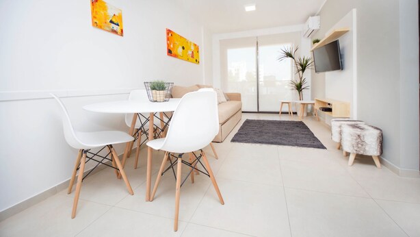 Un salon moderne avec un coin repas, comprenant un canapé, une table basse et un téléviseur fixé au mur.