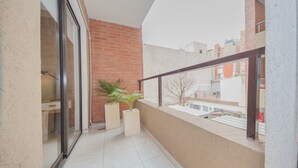 A balcony with a glass door, a brick wall, and two potted plants. - Rent San José de Calasanz WH5 (Córdoba)