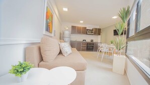 A modern apartment with a living area featuring a sofa and a small table, a kitchen with modern appliances, and a dining area with chairs. - Rent San José de Calasanz WH5 (Córdoba)