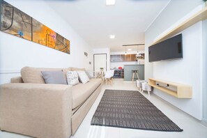 A modern living room with a beige sofa, a black and white patterned rug, and a flat-screen TV mounted on the wall. - Rent San José de Calasanz CX6 (Córdoba)