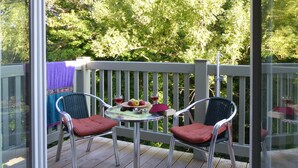 Een terras met twee stoelen en een tafel, een paarse handdoek en een glas wijn op de tafel.