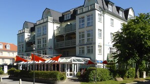 Een hotel met meerdere verdiepingen, balkons, een overdekte ingang en een bord dat aangeeft dat het een hotel is.