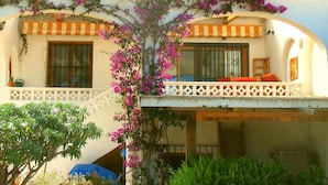A two-story building with a balcony, a covered outdoor seating area, and a garden with bougainvillea. - Charming house with garden, last winter availabilities at short notice! (La Nucia)