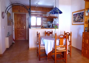 Un comedor con mesa y sillas, una cocina al fondo y un mueble de madera con un arco metálico decorativo.