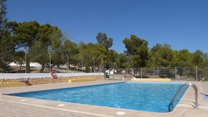 A rectangular swimming pool with a tiled deck, surrounded by a stone wall and metal fencing. - Charming house with garden, last winter availabilities at short notice! (La Nucia)