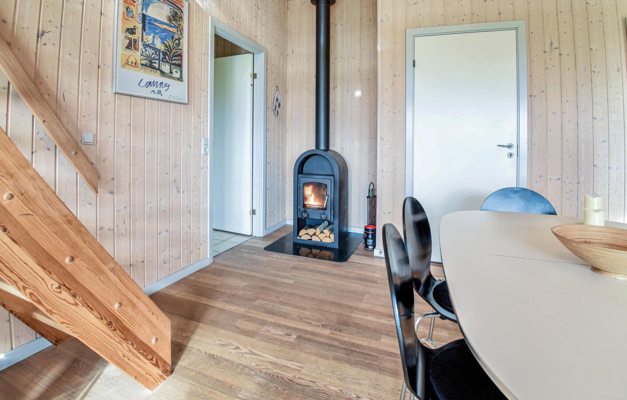 A cozy room with a wooden interior, a fireplace, a dining table with chairs, and a door.
