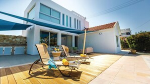 A modern house with a patio area featuring outdoor furniture and a pool.