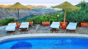 A pool with lounge chairs and a view of the mountains.